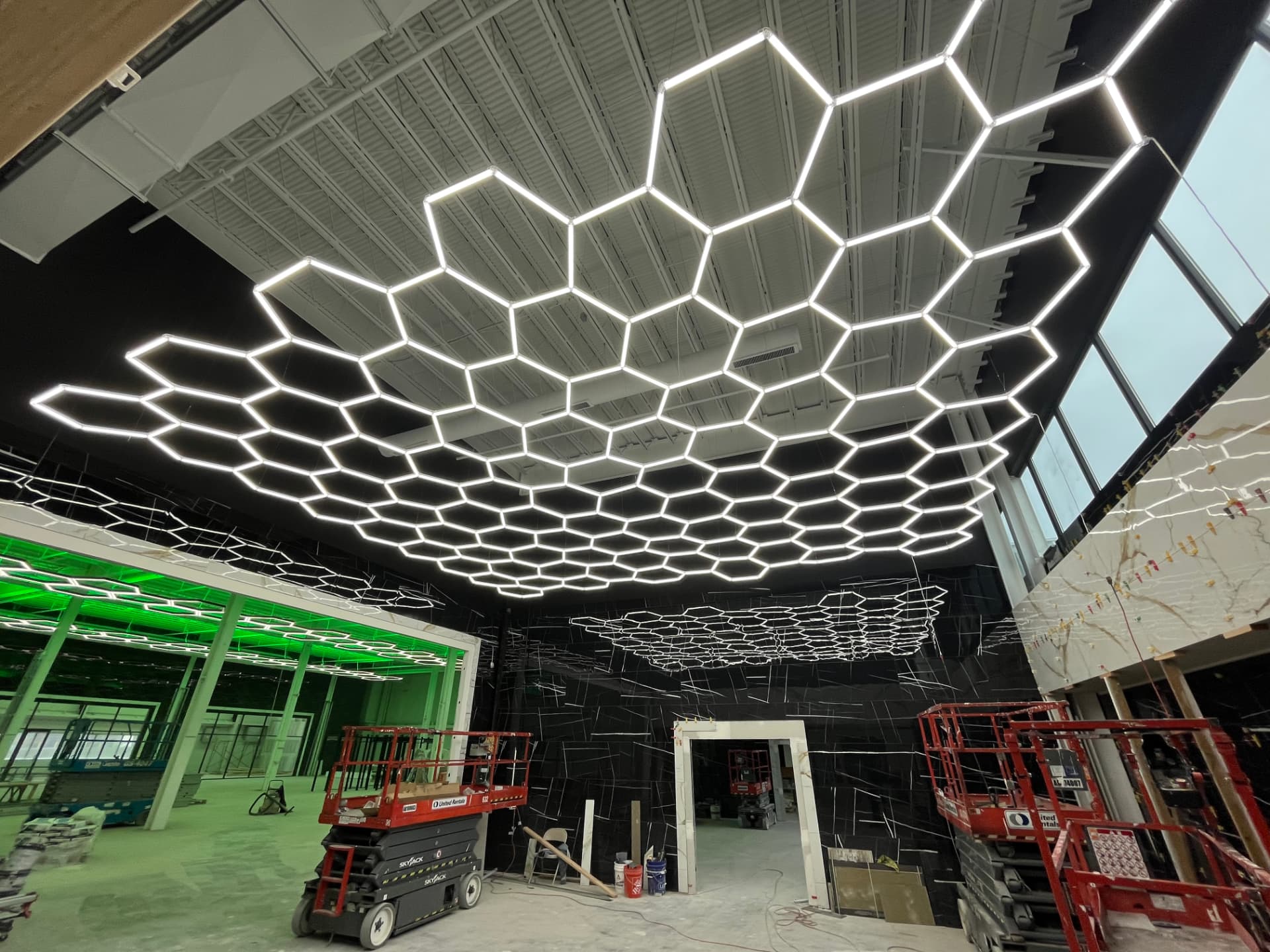 Finished hexagon LED ceiling grid across an open facility floor